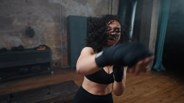 Young African American woman with hand wraps enjoys boxing