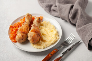 Chicken drumsticks grilled with cabbage salad coleslaw and mashed potatoes in a plate on the table. Healthy food