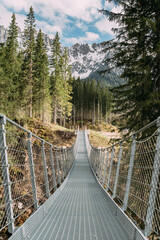 lange Hängebrücke aus Stahl mit schneebedeckten Bergen von Südtirol im Hintergrund in den Dolomiten in Südtirol