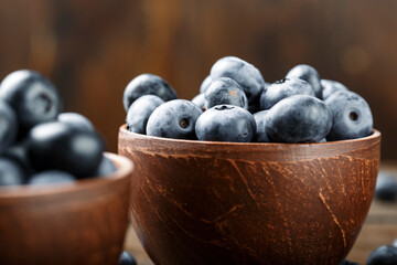Fresh blueberries in a clay bowl and scattered on a wooden table. Foods containing antioxidants.