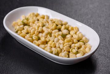 Organics fresh Baby Green Bean Sprouts in white ceramic bowl on a dark concrete background