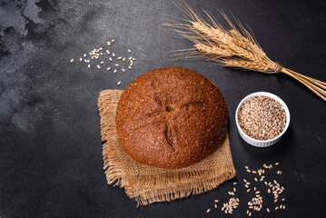 Fresh baked brown bread with ears and grains of wheat