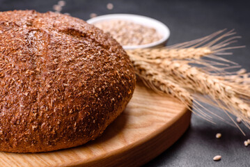 Fresh baked brown bread with ears and grains of wheat