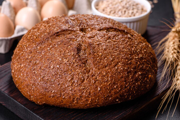 Fresh baked brown bread with ears and grains of wheat
