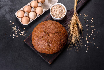 Fresh baked brown bread with ears and grains of wheat
