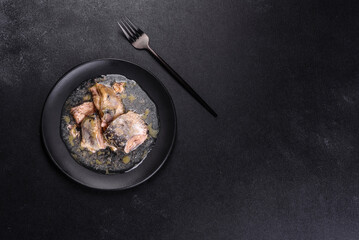 Canned sardine in oil on a black round plate against a dark concrete background