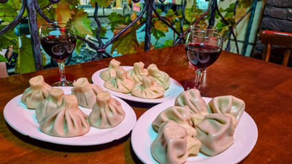 A close up view of a plate of Khinkali, a traditional Georgian dumpling. Georgian red wine. National Georgian cuisine. Top view. Street food. Steamed Dumplings. Tbilisi. Meat wrapped in a bag of dough