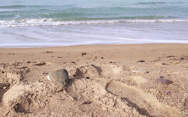 Stones in front of the shoreline of a sandy Agrigento�s beach, small waves of the sea in the background 