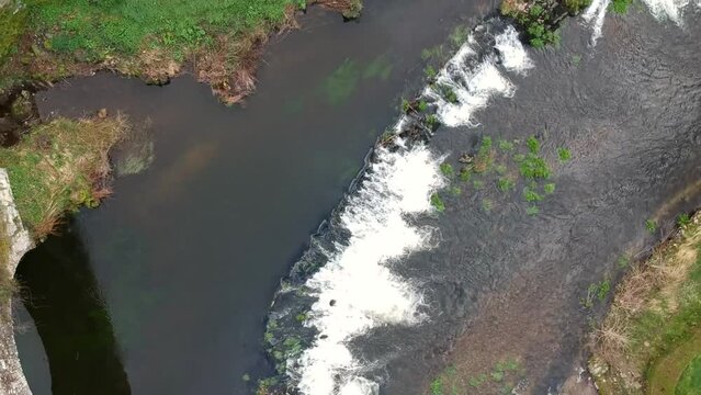 Aerial top down view of the river flow over the step and old bridge