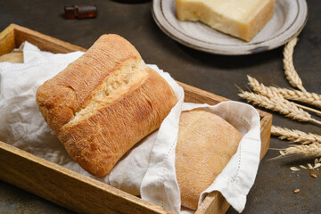 Italian ciabatta bread or bun in a wooden box with white kitchen towel or napkin. Freshly baked traditional bread.  Shallow depth of field