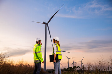 Engineer wearing uniform ,helmet hold document inspection work in wind turbine farms rotation to...