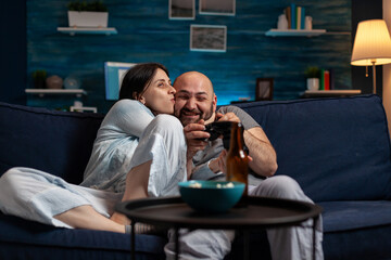 POV of woman kissing man on cheek feeling happy about videogames win, celebrating online cyberspace competition victory. Cheerful couple enjoy winning gaming challenge on tv console.