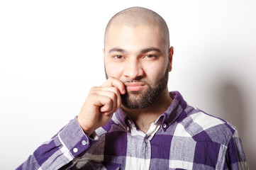 Keeping silent. Portrait of young arabic man in plaid shirt closing his mouth by hand while standing against white background.