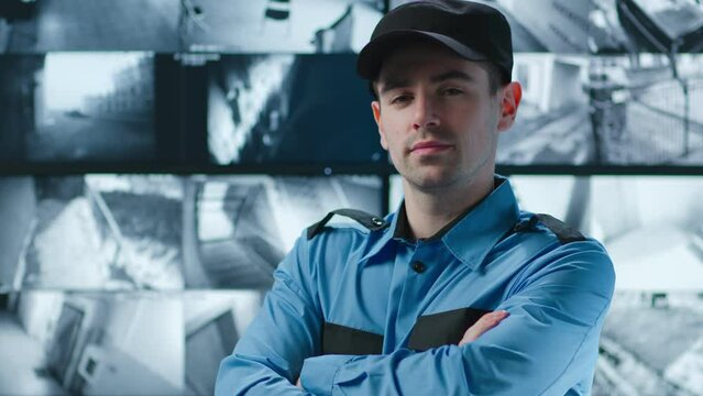 Portrait of security officer with arms crossed posing at camera with monitors on background
