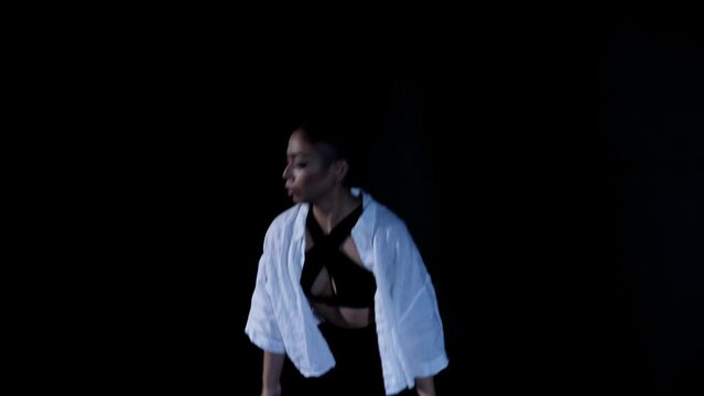 Young Latina Woman Dancing Whacking in Slow Dramatic Emotional Release with White Top on Black Background