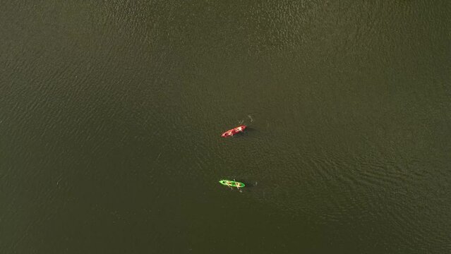 Aerial top view of paddling people with two kayaks on river water during sunny day - Adventure activity in Argentina