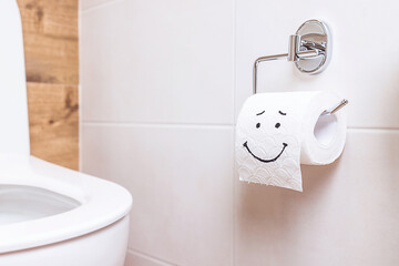 a roll of toilet paper with a happy face hanging on a white wall in the bathroom