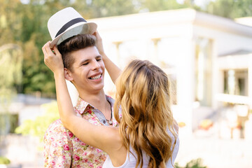 Dating. Loving couple outdoors. Young woman taking off boyfriend's hat.