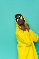 Black woman in yellow hoodie and sunglasses looking up