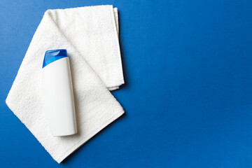 Cosmetic shampoo bottle mockup with towels on a colored table. Bathroom background, toilet accessories for hand and body care