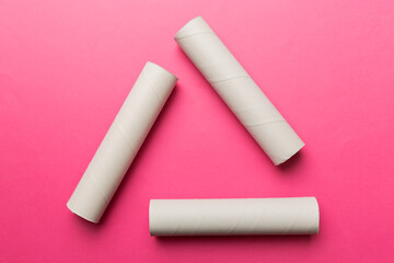 Empty toilet paper roll on colored background. Recyclable paper tube with metal plug end made of kraft paper or cardboard in the form of a recycling sign