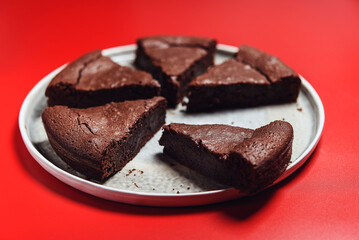 Chocolate Flourless Cake on red background. Soft chocolate gÃ¢teau or Brownie cake. Selective focus