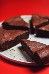 Chocolate Flourless Cake on red background. Soft chocolate gÃ¢teau or Brownie cake. Selective focus