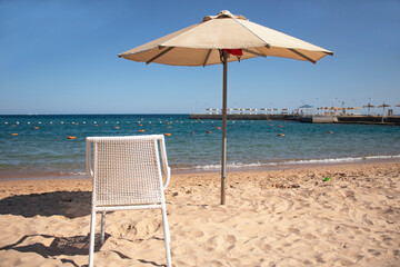 beach umbrella and chair on the beach next to the sea