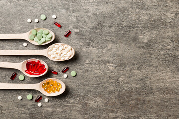 Top view Variety of vitamin and mineral pills in wooden spoon on Colored background. Top view of assorted pharmaceutical medicine pills. Dietary supplement healthcare product
