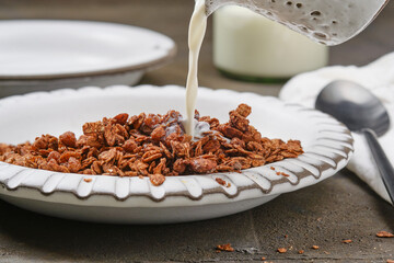 Bowl of muesli with pouring milk. Healthy Breakfast. Healthy chocolate granola in a bowl. Shallow depth of field