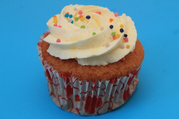 Sweet cake with tutti frutti sprinkles on top on the wooden table white background.