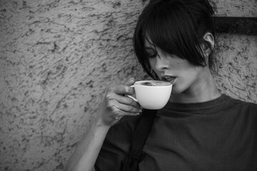 Portrait of a joyful young woman enjoying a cup of coffee. Smiling beautiful girl drinks coffee. 