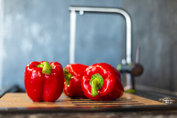 Close-up of red bell pepper on the background of a tap with water, wash vegetables.