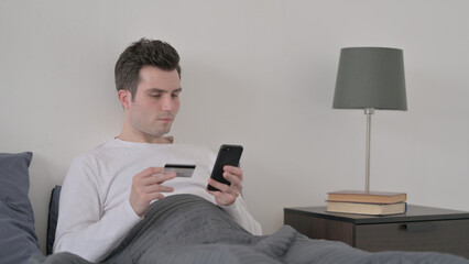 Man Making Online Payment on Smartphone in Bed