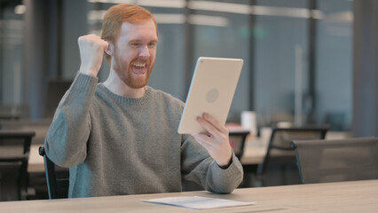Young Man Celebrating Success on Tablet in Office 