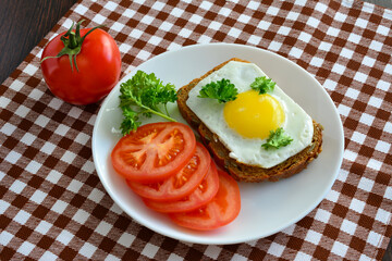 sandwich with fried egg decorated with parsley and tomato slices, close-up