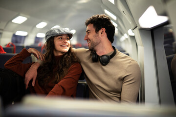 Loving couple travel by train. Happy woman and man talking while sitting in the train