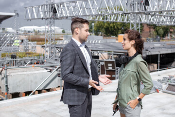 Event managers discuss stage construction. Installation of stage equipment and preparing for a live concert open air. Event manager portrait. Summer music city festival. Teamwork. - 499107503