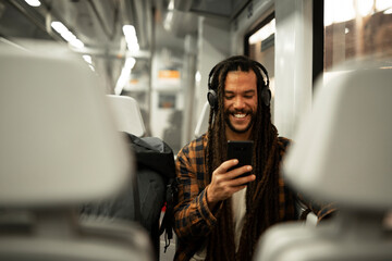 Young man listening the music while traveling by a train. Handsome young man traveling by a train