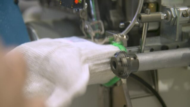 Close-up of overlock foot and cutter overlocking cuff in glove manufacturing. . The overlock machine trims the edges of the fabric. garment factory