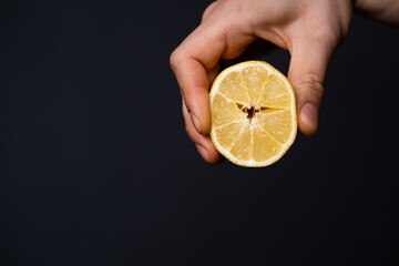 Man holds a lemon in his hand on the dark background.