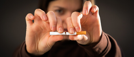 Girl breaks a cigarette in her hands, view closeup.
