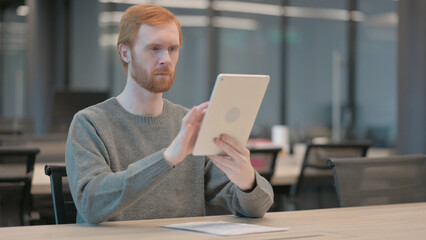 Young Man using Tablet while Sitting in Office