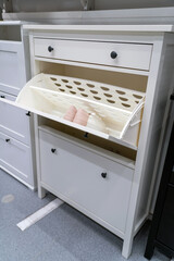Open white wood shoe storage cabinet with sports shoes inside