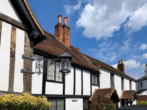 Cookham village, England, Berkshire. Church gate street view. Old half timbered house opposite Holy Trinity church in medieval village White facade with black beams red tile roof chimney old lantern