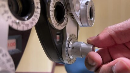 African American Man adjusting dials on phoropter used for eye examination or testing for eye glasses in ophthalmology, optometry, and optician offices