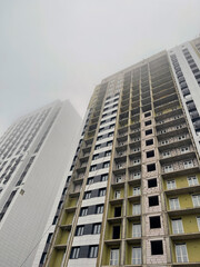 Fototapeta premium Facade of modern building in city. From below of constructing exterior of contemporary multistory building with glass mirrored windows against cloudy sky