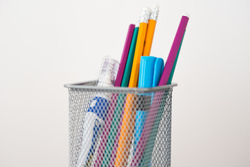 Glass for pencils and pens on a white background. Focus on pencils.