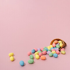 Colorful Easter Eggs fell out of the ice cream cone on pastel pink background with copy space for greeting message. Minimal Easter concept combined with summer vibe.