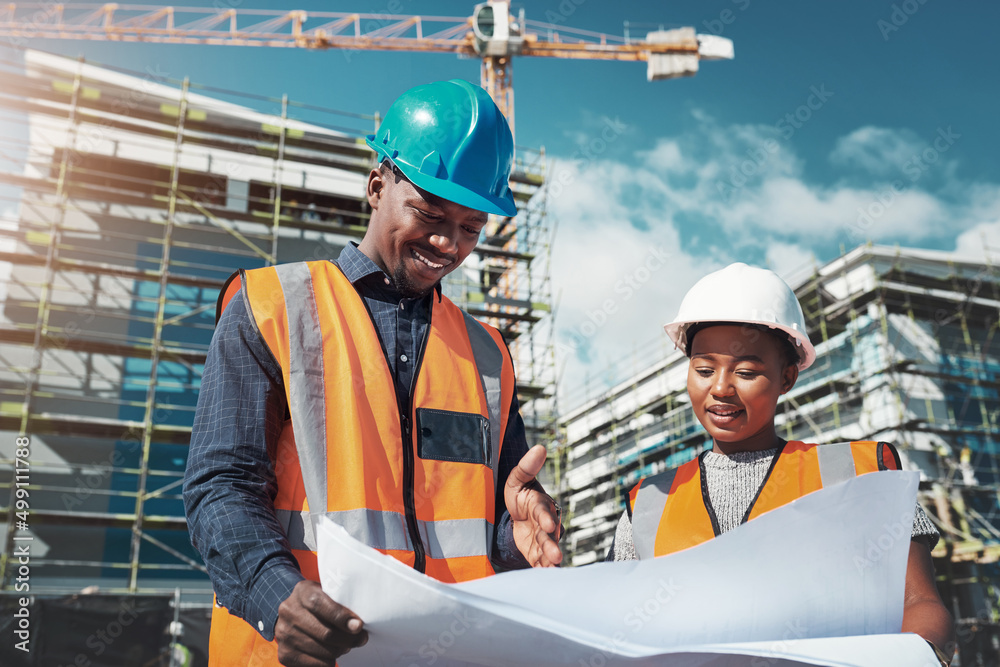 Poster Running a job site is a joint effort. Shot of a young man and woman going over building plans at a construction site.